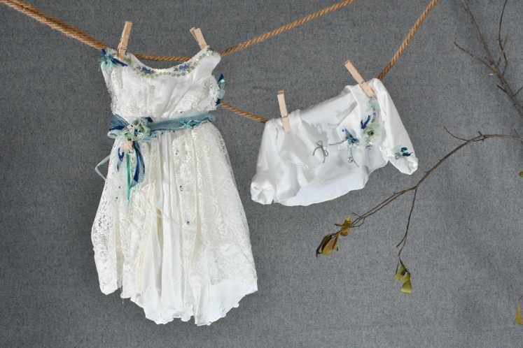 Ένα βαθιά boho βαφτιστικό σύνολο για κορίτσι με χρωματιστές λεπτομέρειες που περιλαμβάνει:  Φόρεμα (φόδρα από 100% βαμβάκι) λευκό με στρώση δαντέλας, στολισμένο με χειροποίητα υφασμάτινα λουλούδια και κουμπιά Στεφανάκι ή καπελάκι με χειροποίητα λουλούδια Μπολερό με ασορτί λεπτομέρειες  Μπαλαρίνες διακοσμημένες με λουλούδια